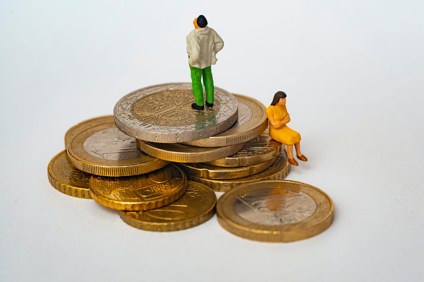 Photo by Mathieu Stern on Unsplash - Man and woman on stack of coins.